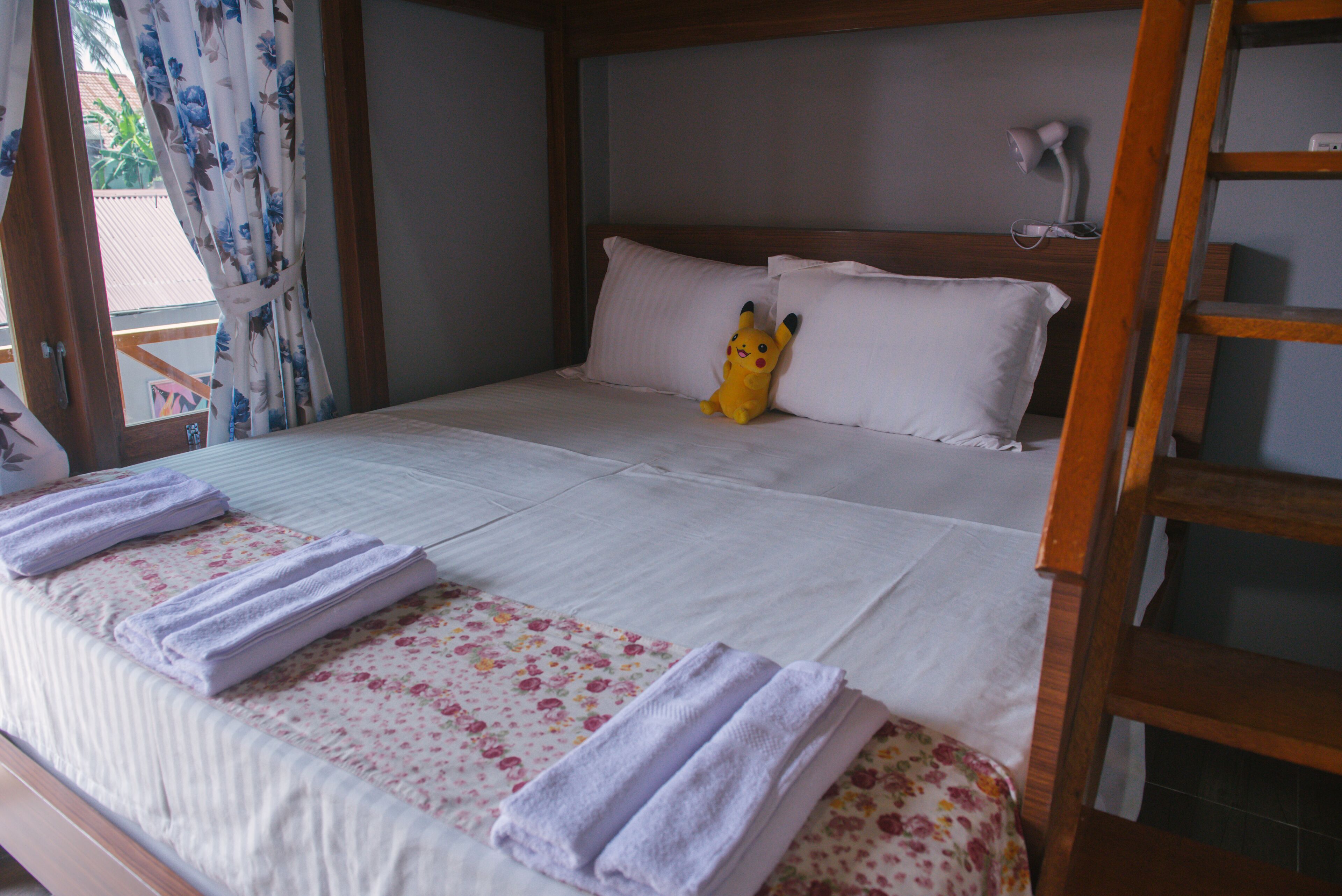 A neatly made bed with white linens and a floral-patterned bedspread.
