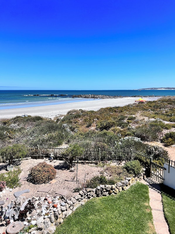 A coastal landscape with a sandy beach, rocky terrain, and sparse vegetation. - Baywatch Villa Guest House and Self Catering Accommodation (Paternoster)
