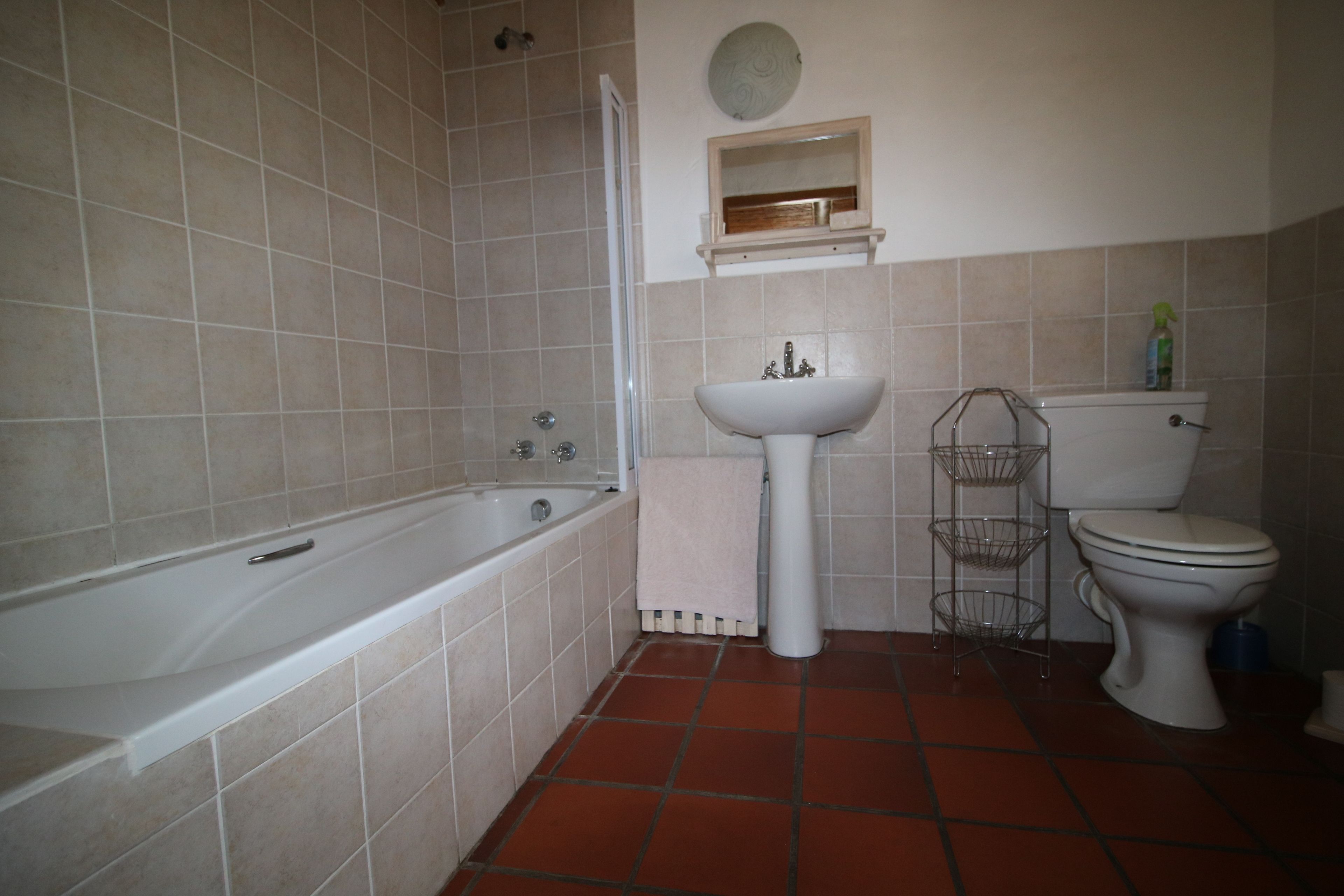 Une salle de bain équipée d’une baignoire, d’un lavabo, de toilettes et d’une étagère contenant des articles de toilette.