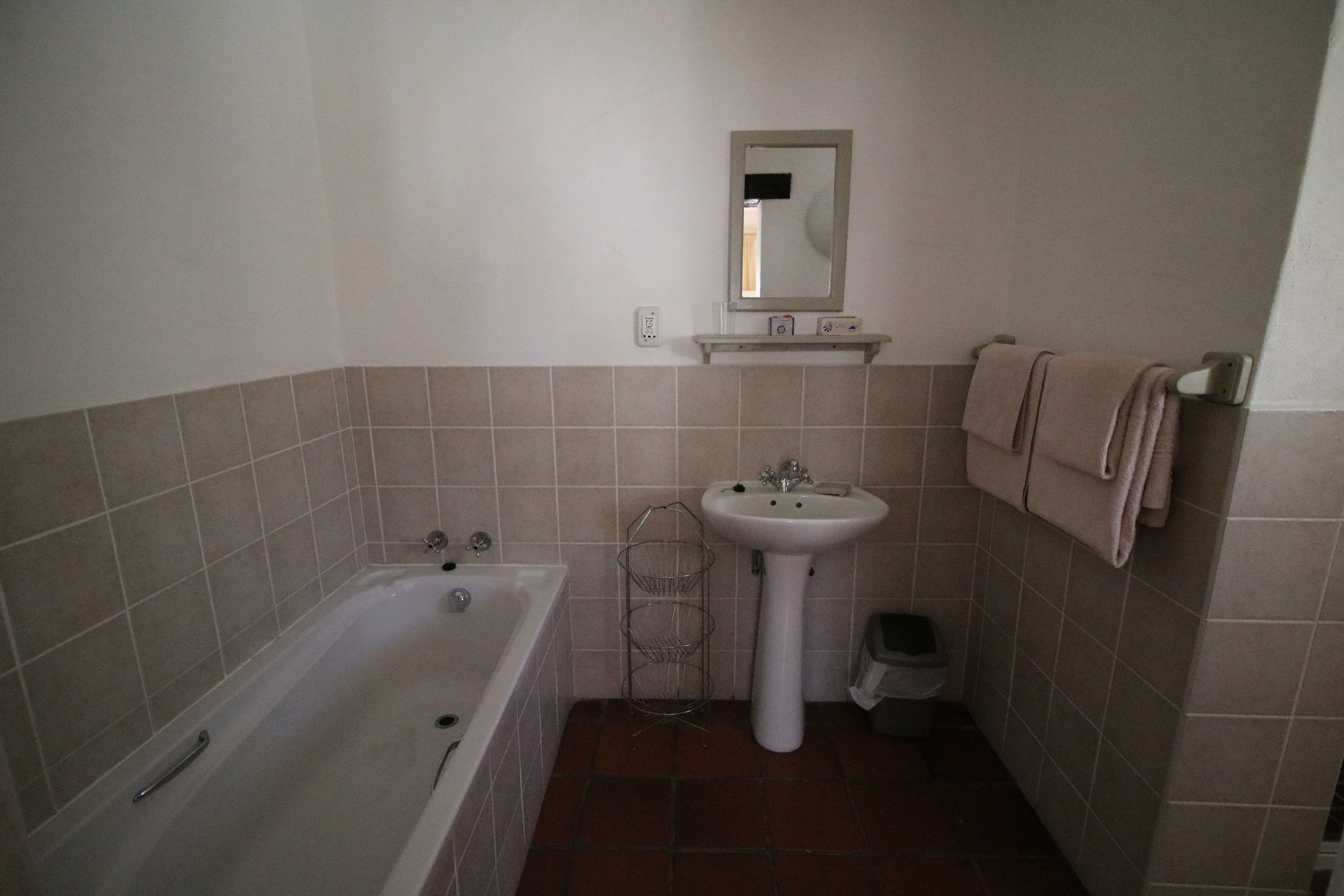 Un baño con bañera, lavamanos, espejo y toallero.
