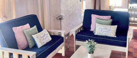 Een gezellige kamer met twee blauwe banken, een witte tafel en een houten plafond.
