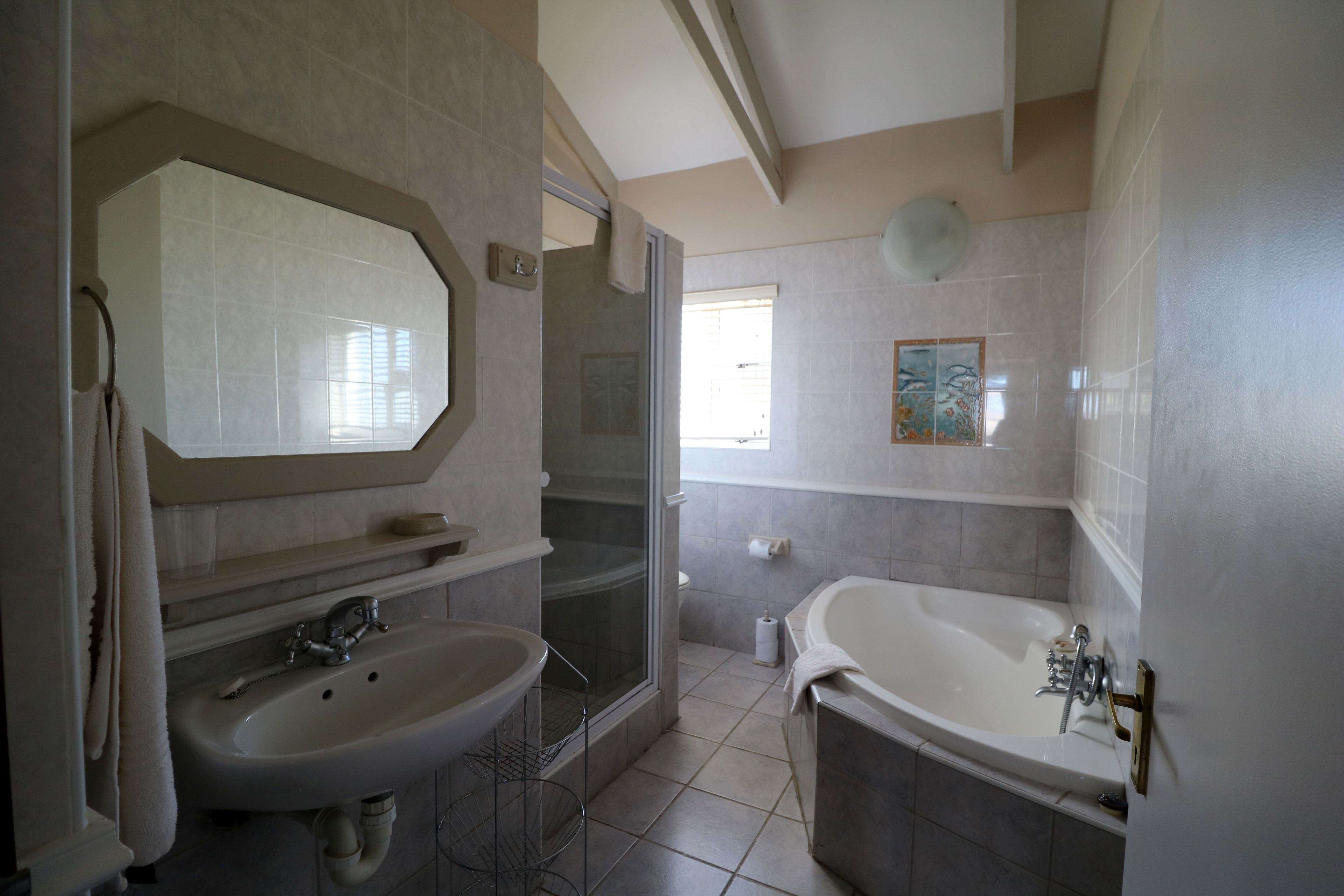 A bathroom with a sink, mirror, shower, and bathtub.