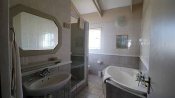 A bathroom with a sink, mirror, shower, and bathtub.