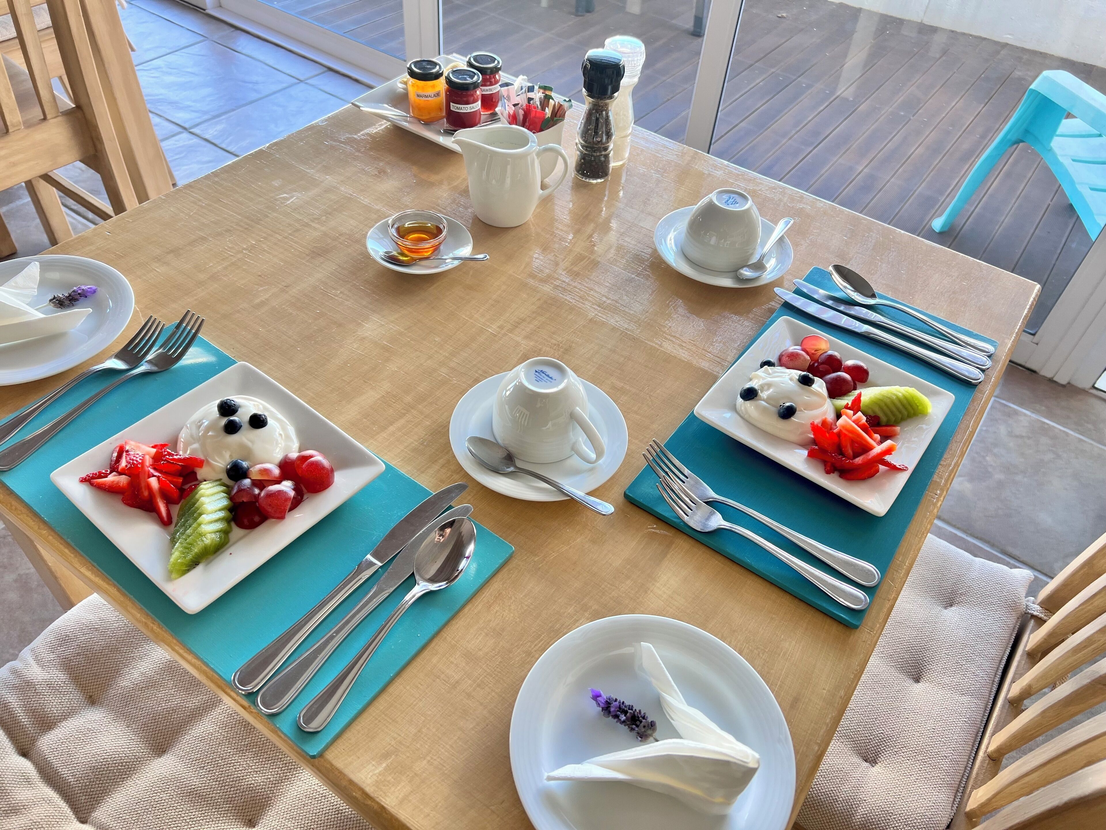A dining table set with plates of fruit, a pitcher, and condiments.