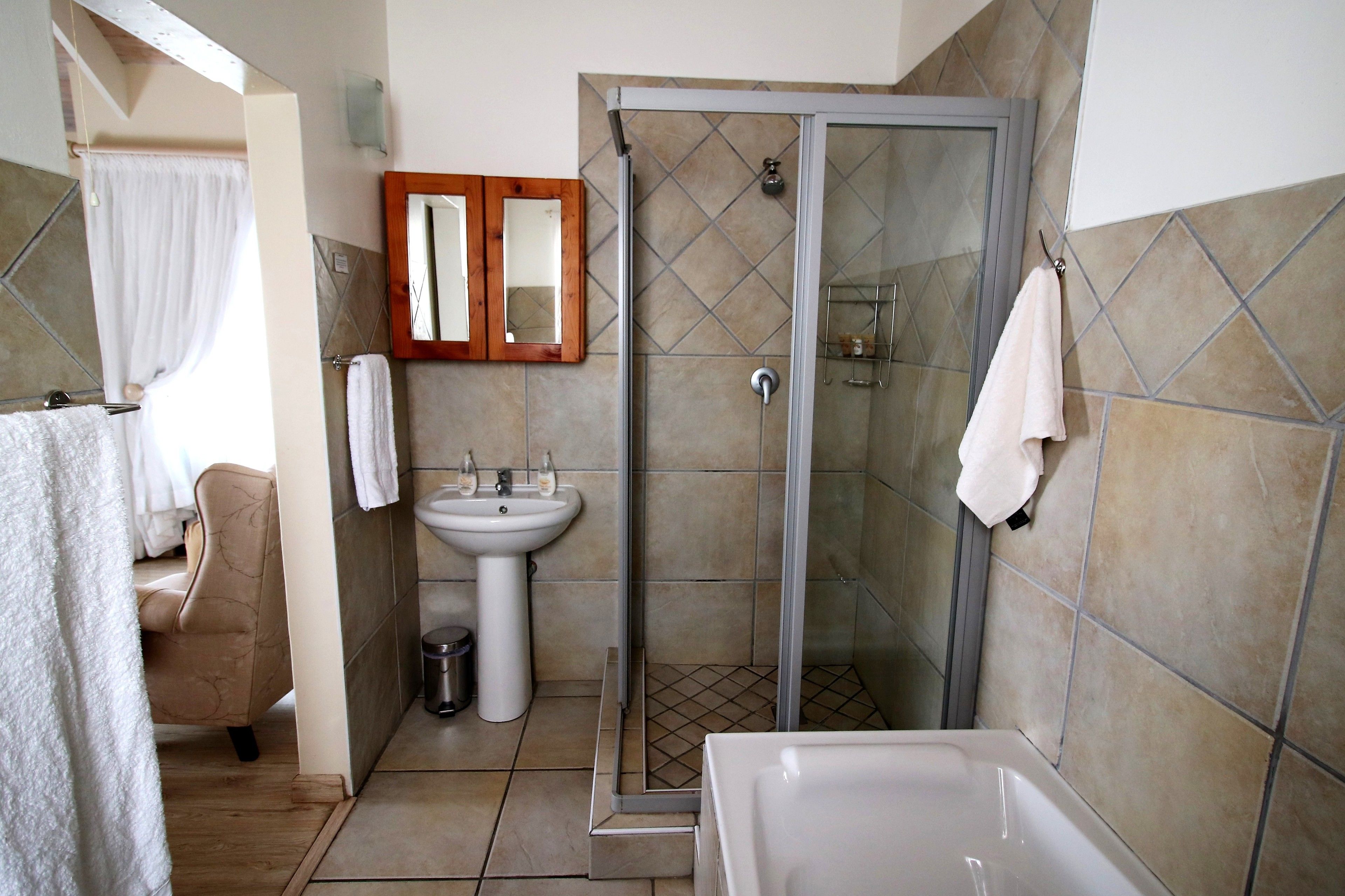 Een badkamer met douche, wastafel en bad.