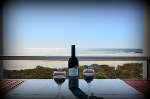 Una mesa con una botella de vino y dos copas, con vistas a una playa y al océano.