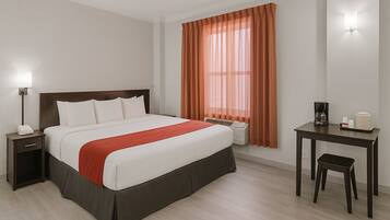 A hotel room with a bed, bedside table, lamp, desk, chair, and a window with curtains.