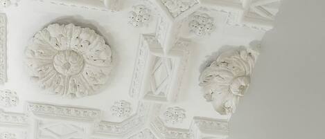 Un techo con intrincados diseños blancos decorativos, que incluyen motivos florales y formas geométricas.
