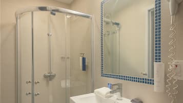A modern bathroom with a glass shower enclosure, a white sink, and a large mirror with a blue-tiled border.