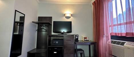 Hotelkamer met twee bedden, een bureau met een televisie, een koffiezetapparaat, een minibar, een verwarming en een raam met gordijnen.