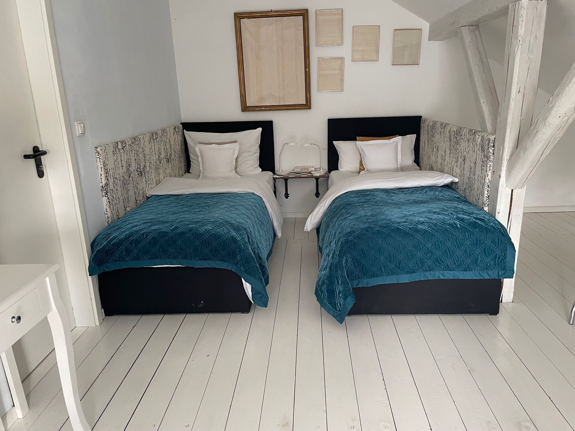 Habitación doble con dos camas, paredes blancas y suelo de madera.