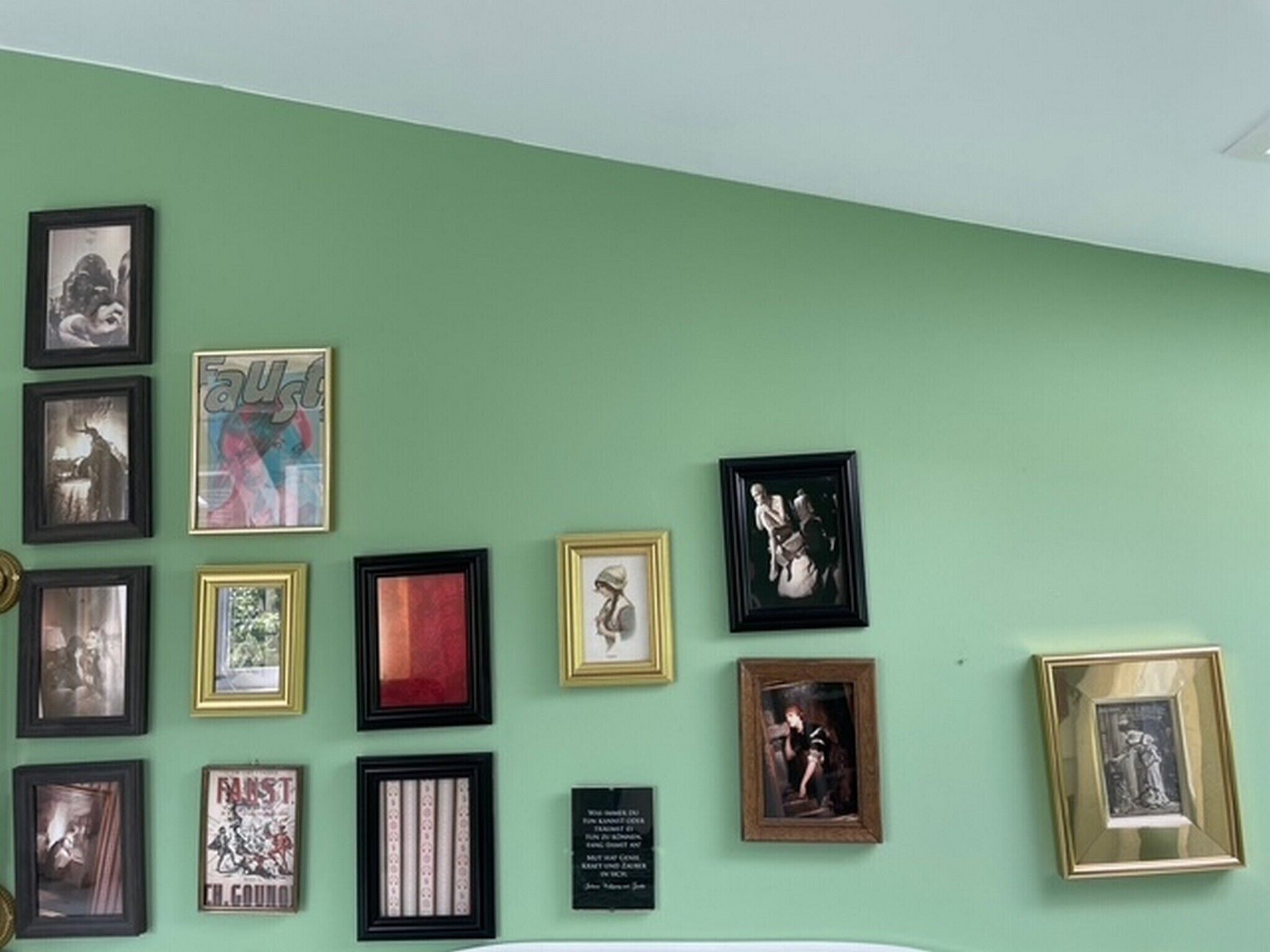 Un mur orné de divers tableaux encadrés et d’une plaque commémorative.