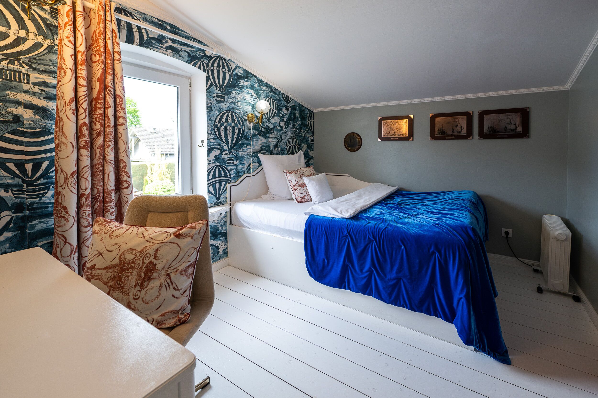 Een slaapkamer met een bed, een stoel, een radiator en een raam met gordijnen.