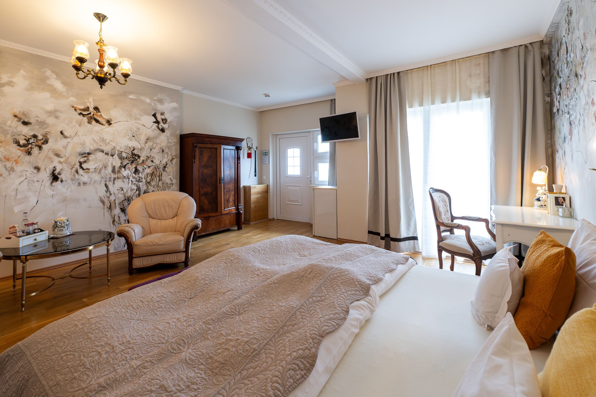A hotel room with a large bed, a desk, a chair, a television, and a wall with a unique design.