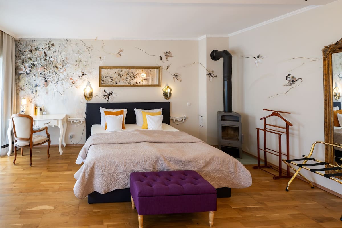 Un dormitorio con cama, una silla, un escritorio, una chimenea y un espejo.