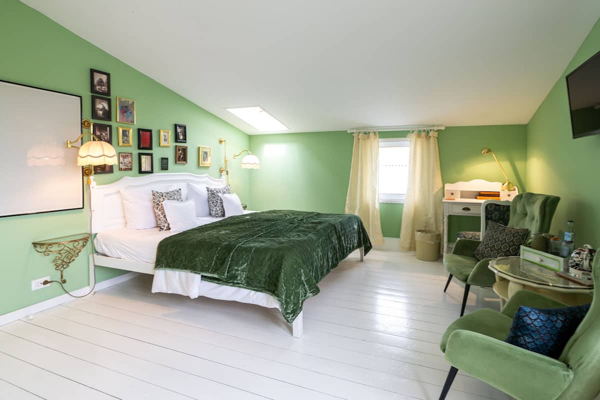Un dormitorio con cama, una silla, un escritorio y una ventana con cortinas.