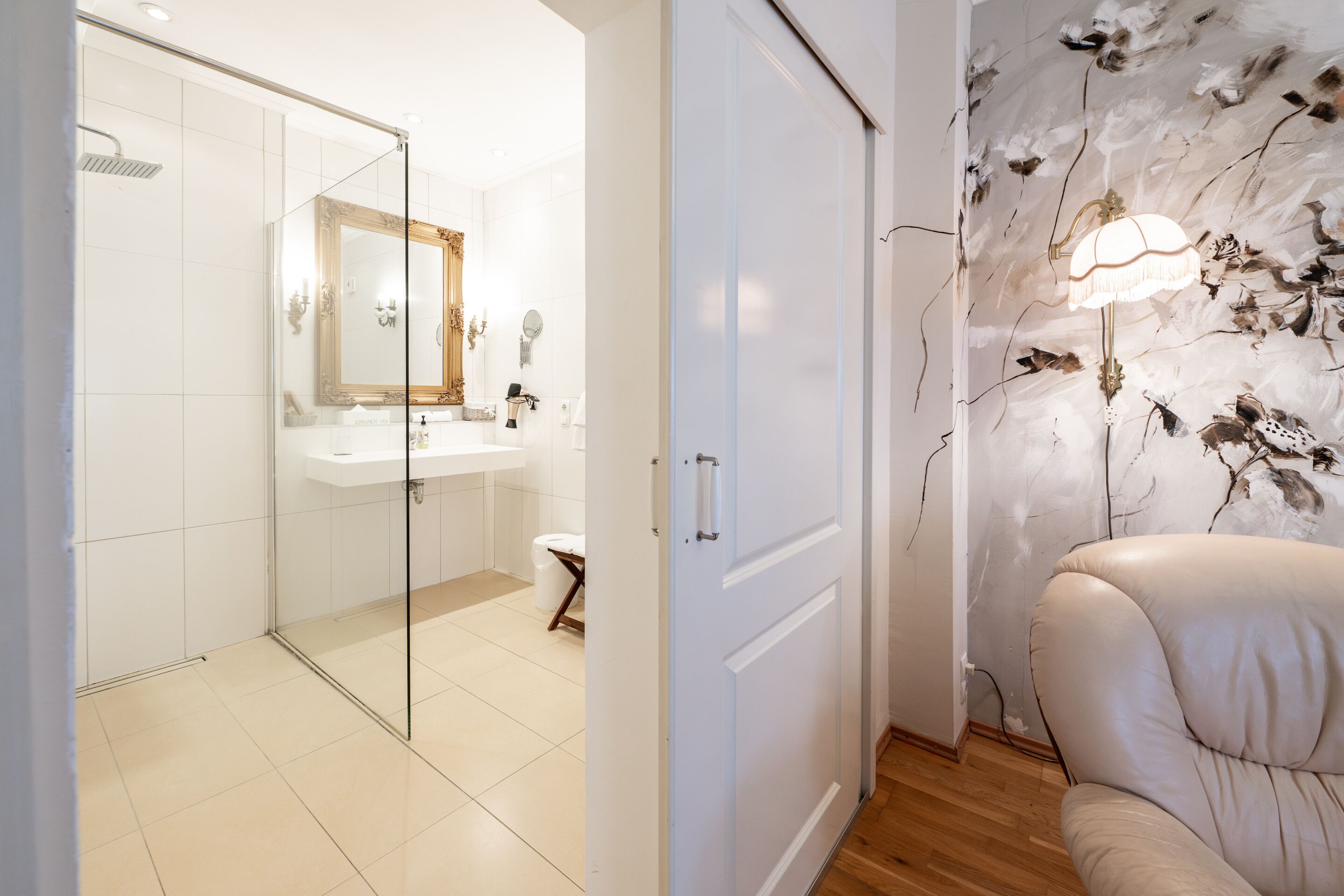 A modern bathroom with a glass shower enclosure, a white sink, and a decorative mirror.