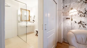 A modern bathroom with a glass shower enclosure, a white sink, and a decorative mirror.