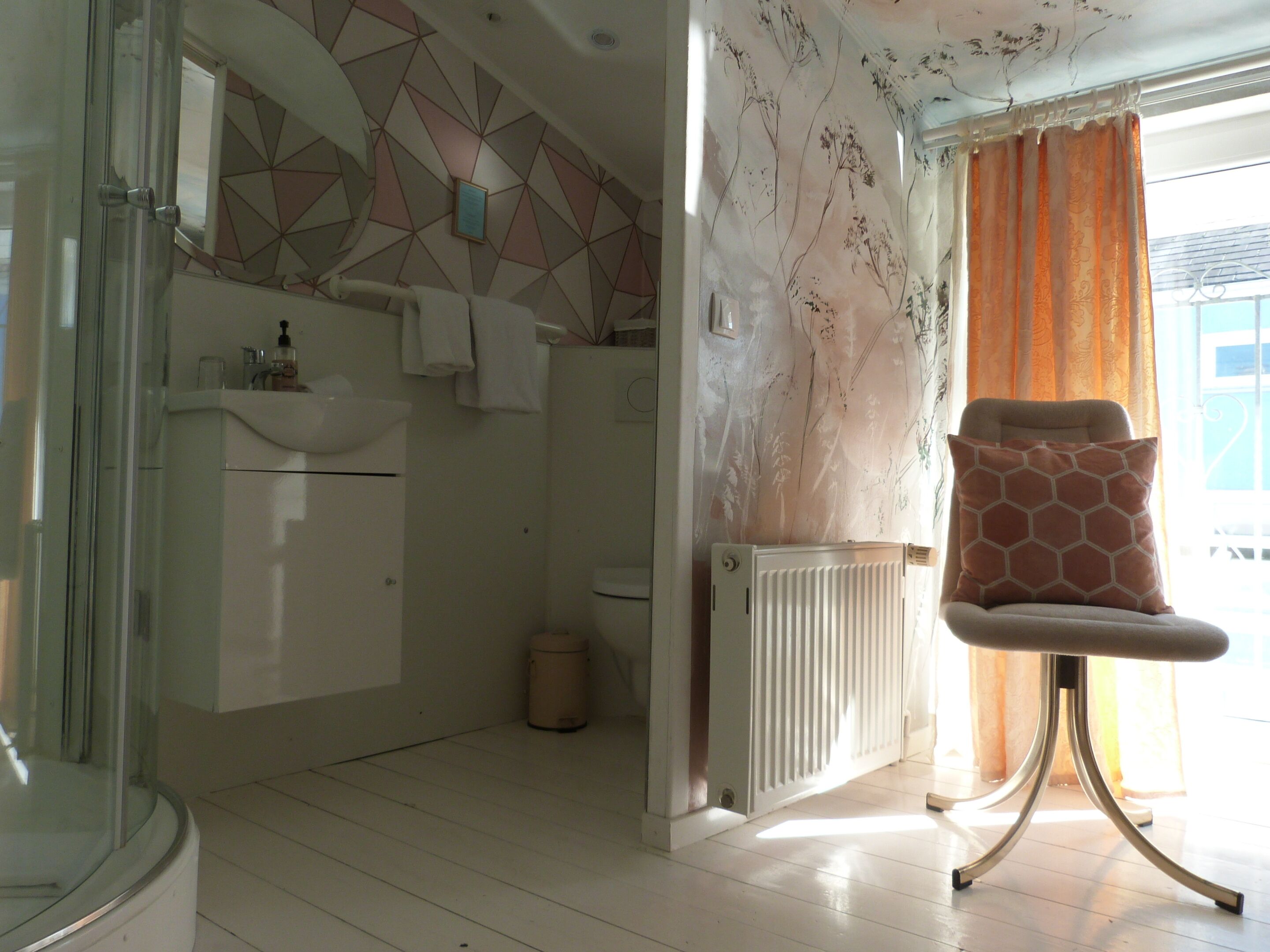 Et badeværelse med væg i geometrisk mønster, en hvid vask, et toilet og en radiator.