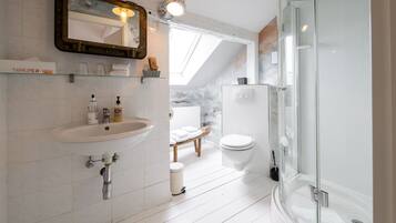 A modern bathroom with a sink, mirror, and shower.