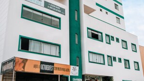 A multi-story hotel with a green and white facade, balconies, and a sign for 'Odontologia Benini' on the ground floor. - Blu Terrace Hotel (Blumenau)