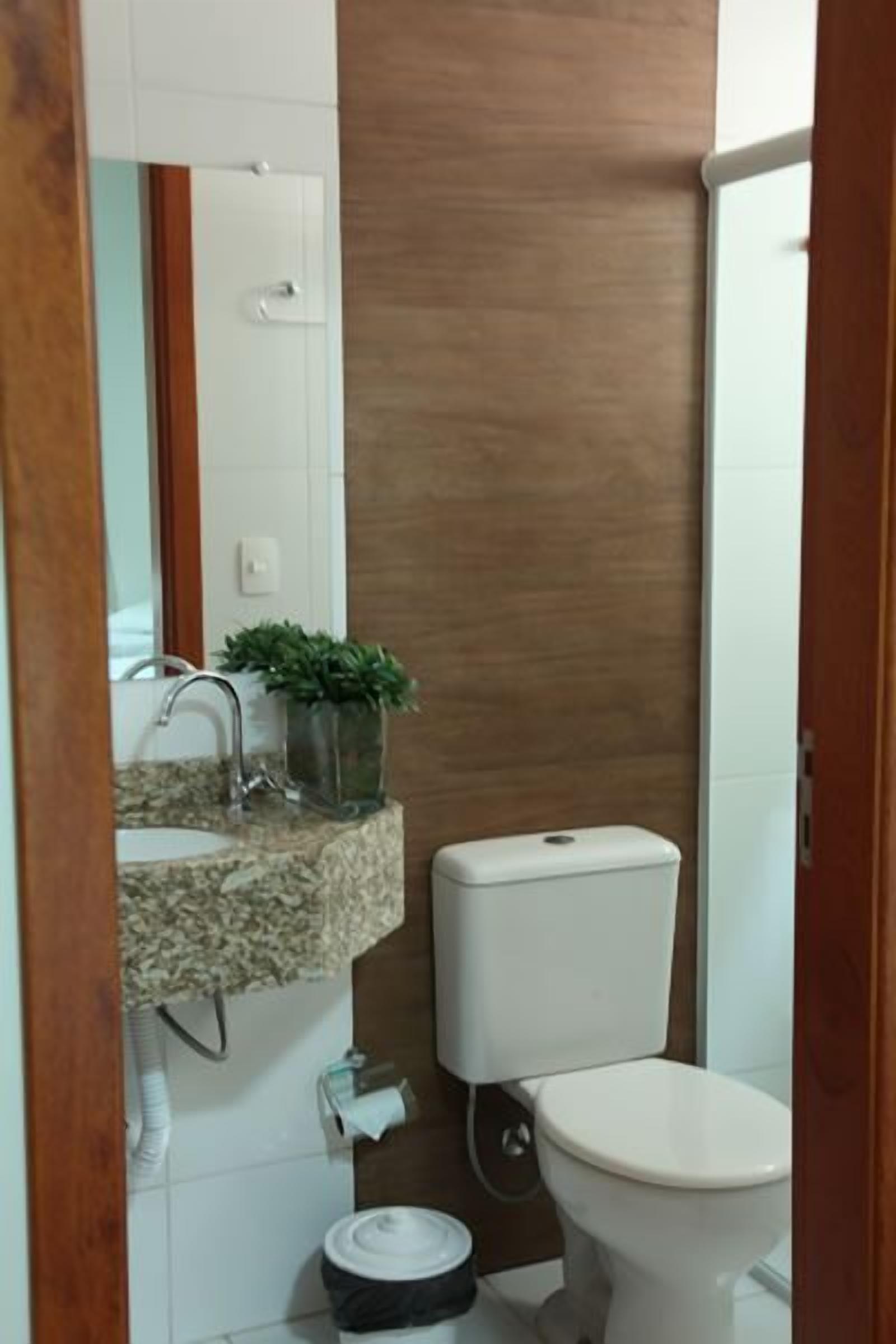 A bathroom with a toilet, sink, and a mirror.