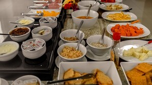 A buffet table with various food items and utensils. - Blu Terrace Hotel (Blumenau)