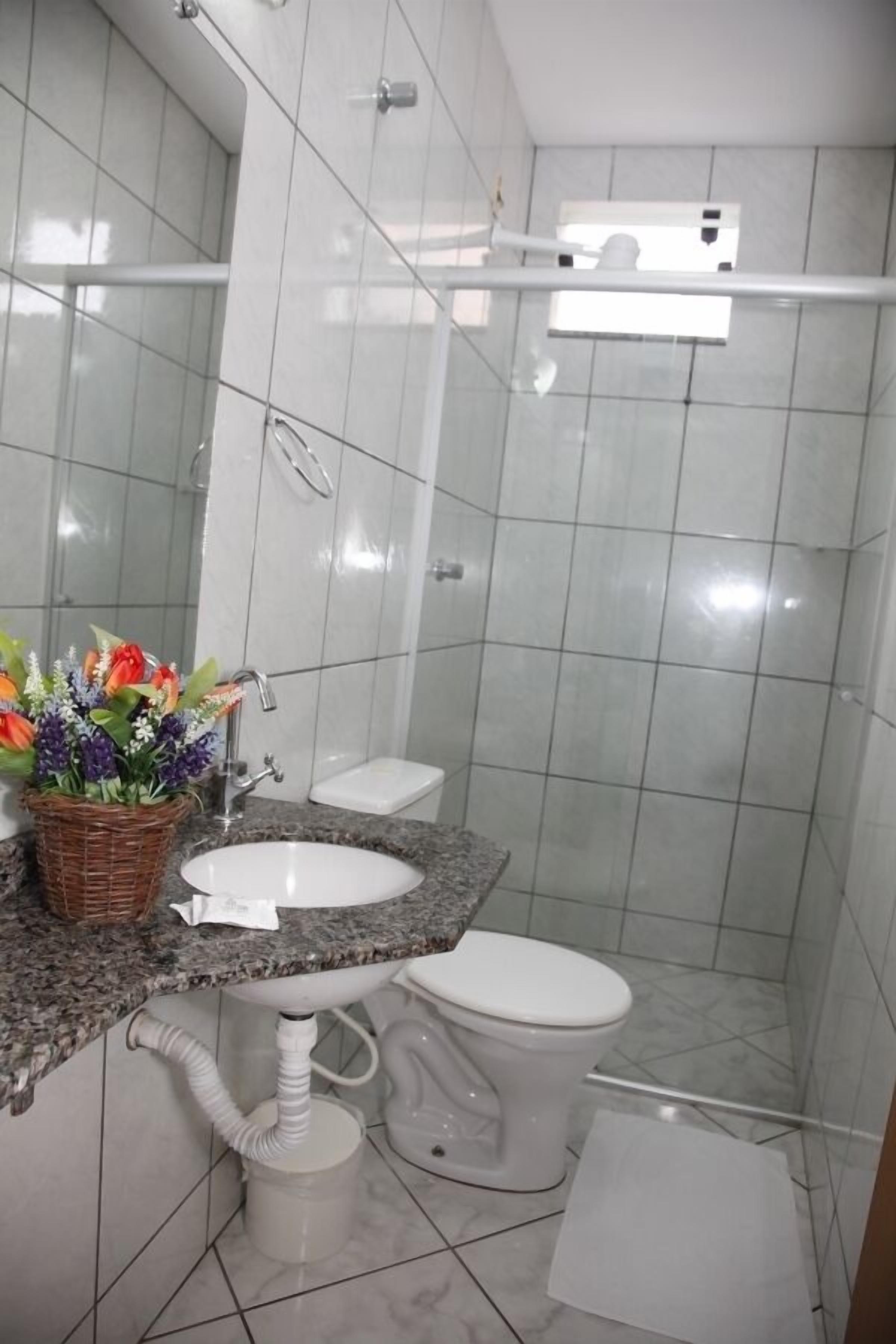 A bathroom with a white sink, toilet, and shower area.
