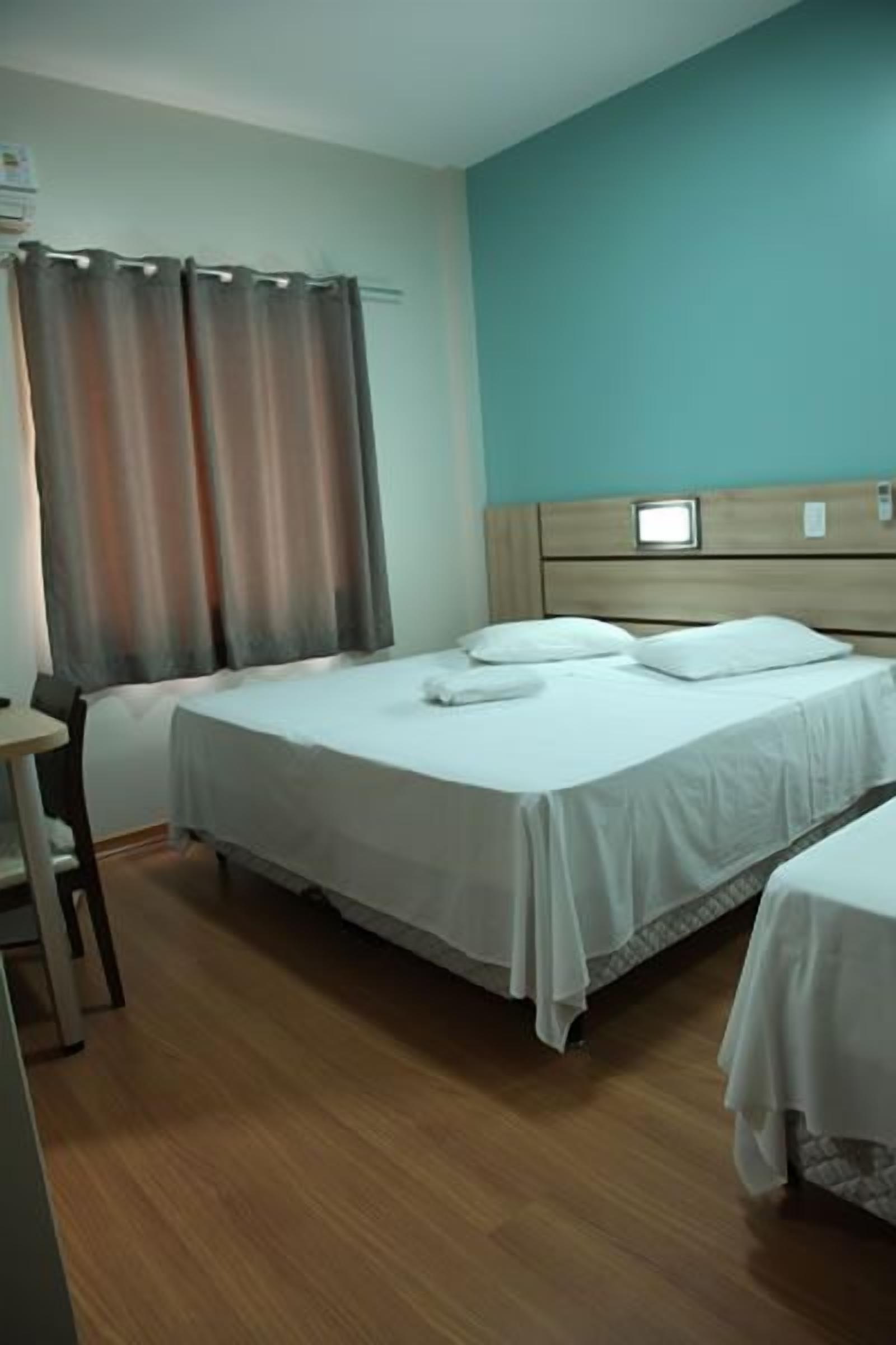 Habitación de hotel con dos camas, un escritorio y un televisor sobre el cabecero.