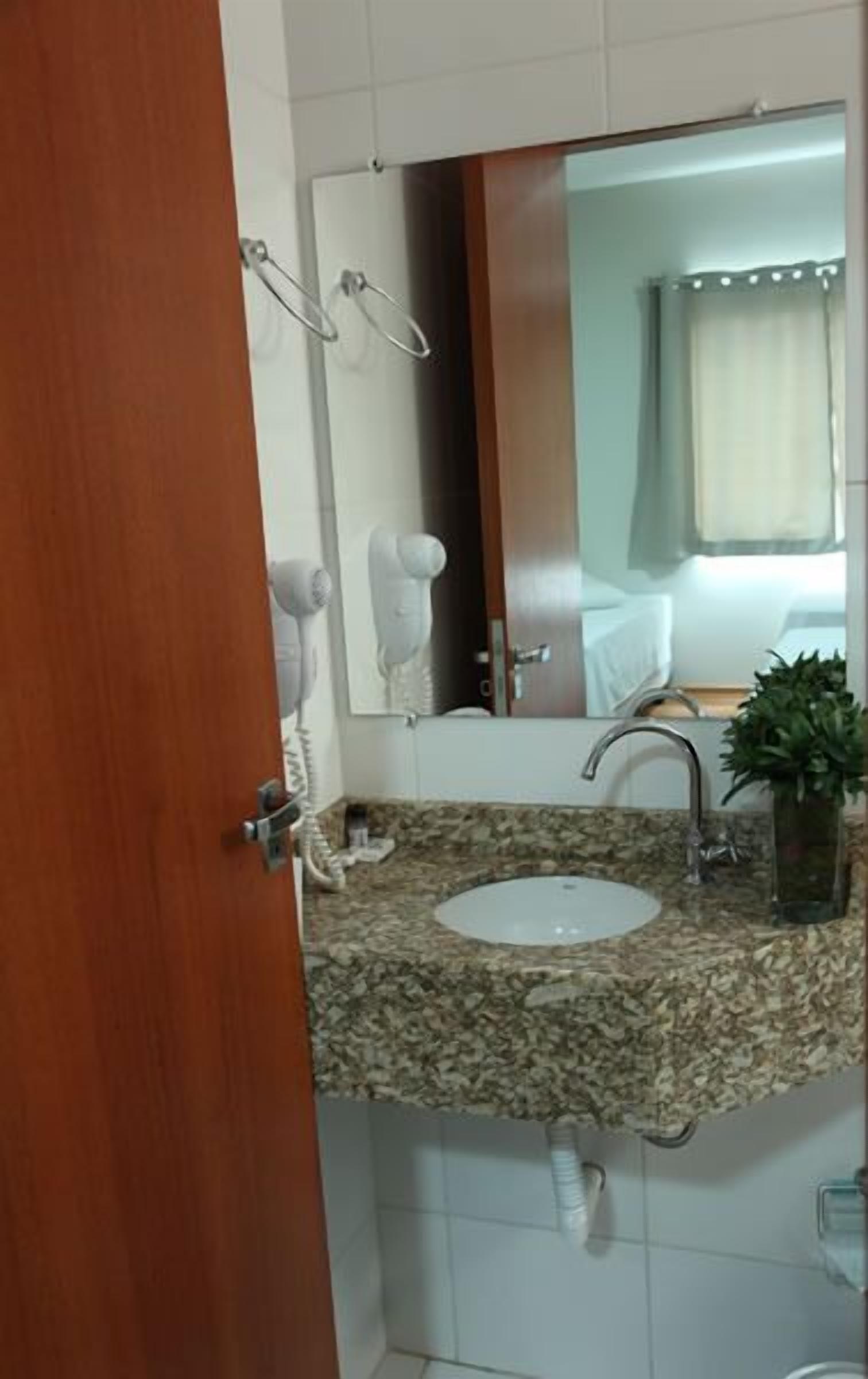 Un baño con lavamanos de encimera de granito, un espejo y un perchero para toallas.
