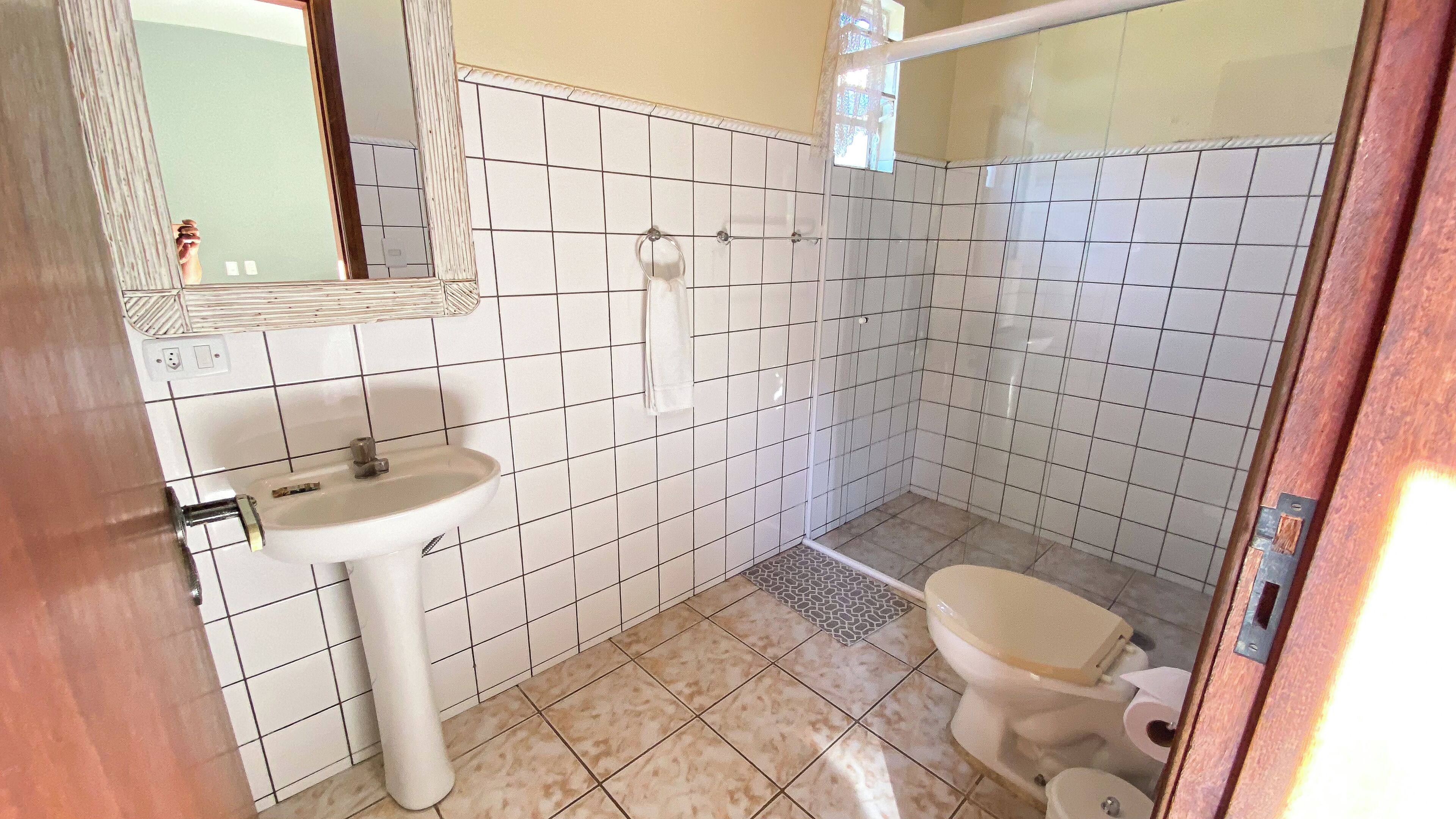 Un baño pequeño con azulejos blancos, un lavabo, un inodoro y una zona de ducha.
