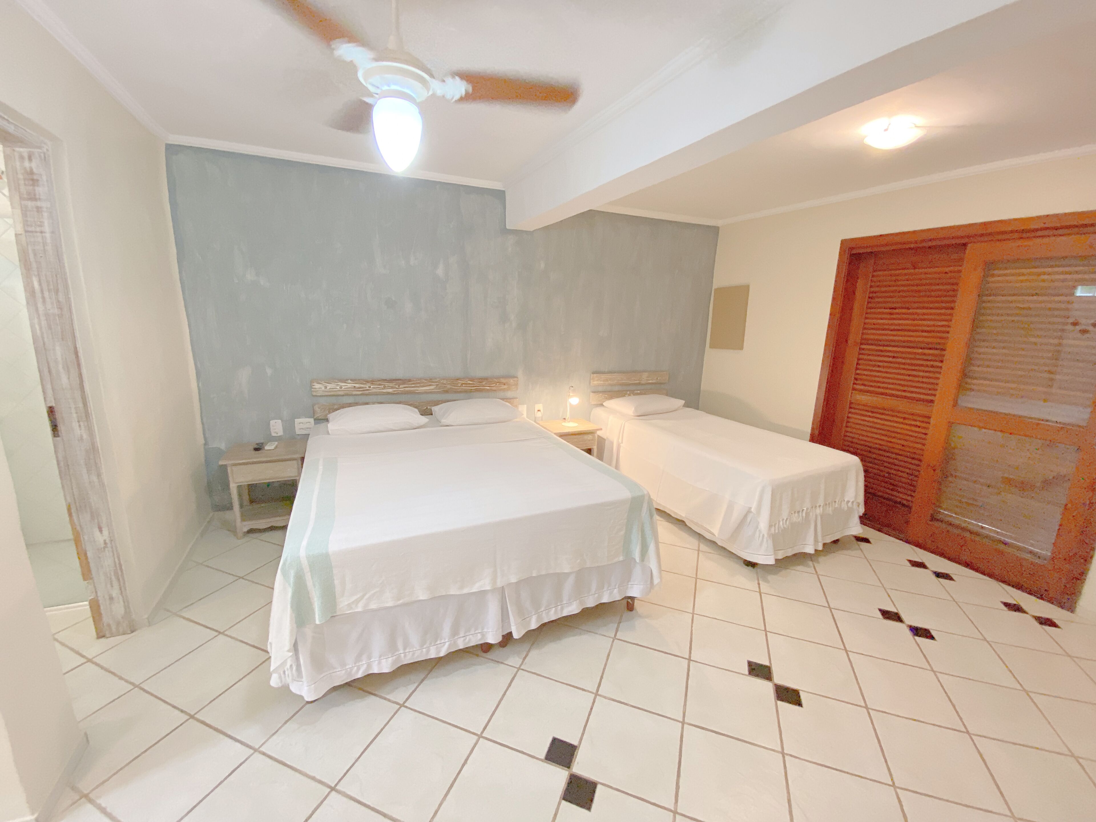 Un dormitorio con dos camas, ventilador de techo y suelo de baldosas.