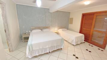 Un dormitorio con dos camas, ventilador de techo y suelo de baldosas.