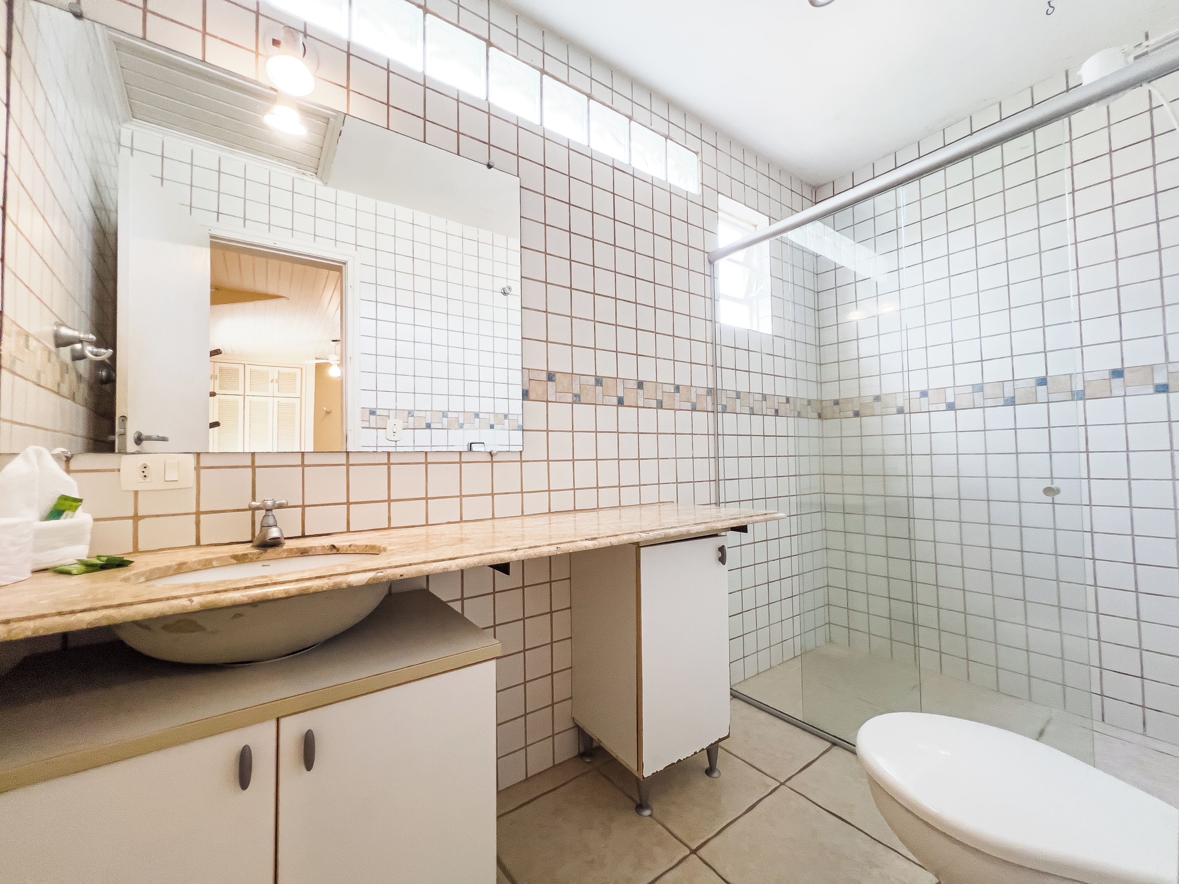 A modern bathroom with a sink, mirror, and shower area.