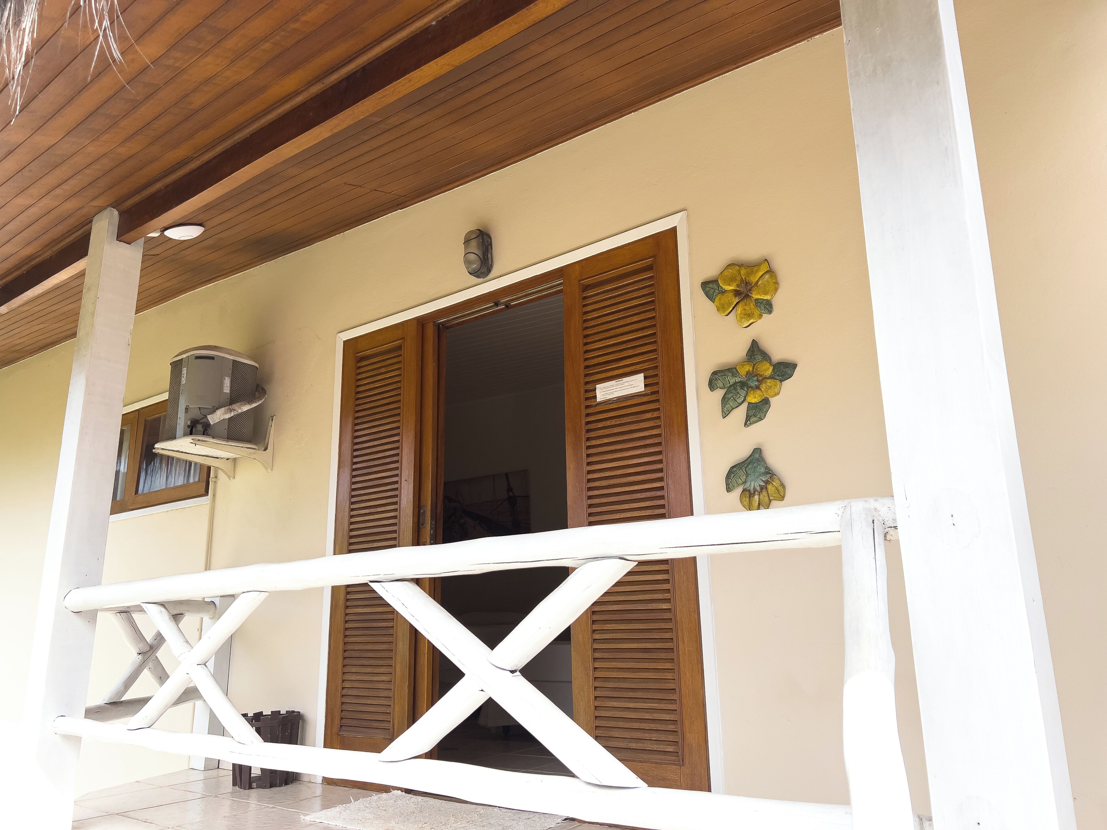 A building entrance with a wooden door, a window, and a wall-mounted air conditioning unit.