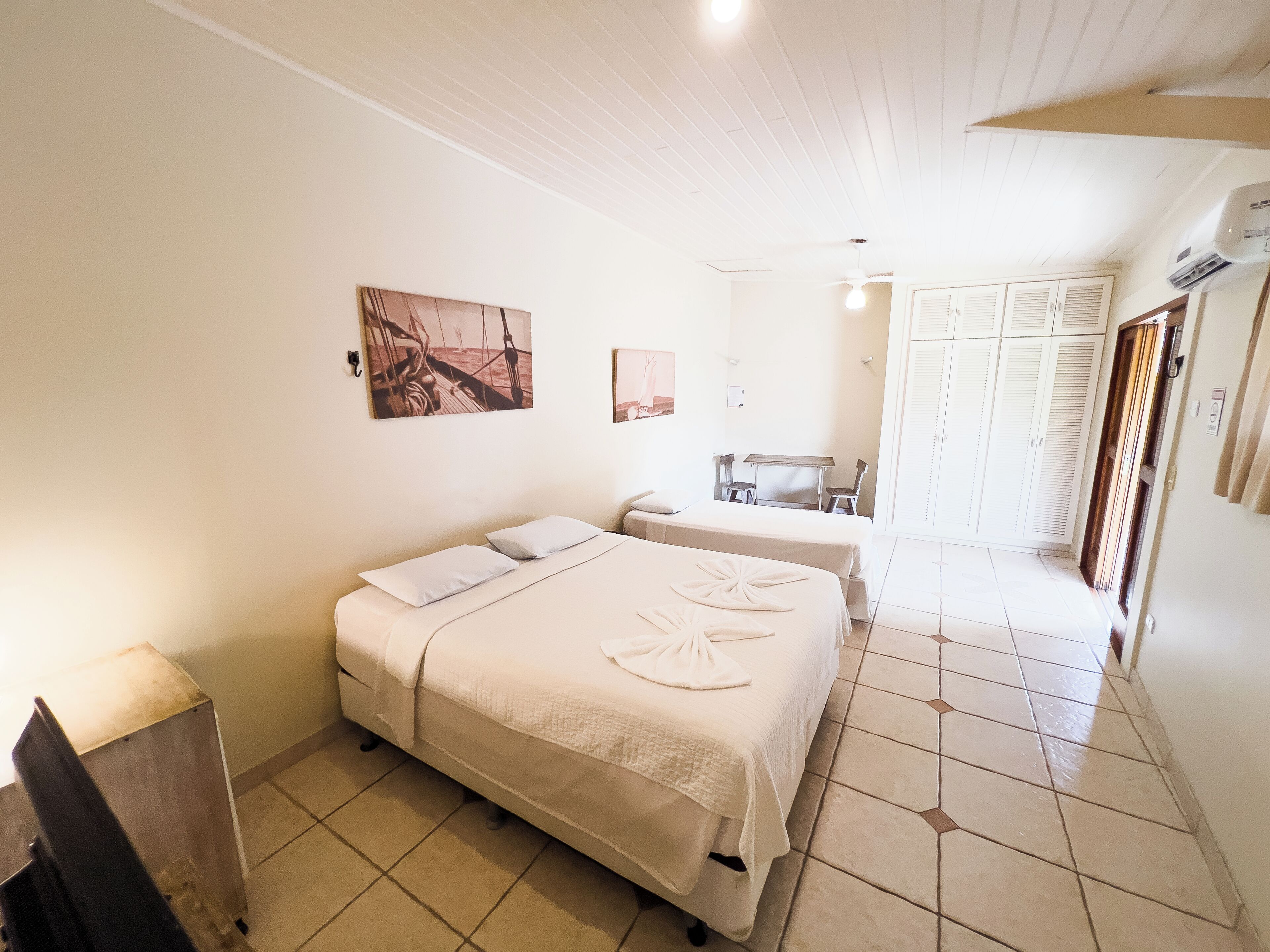 Een slaapkamer met twee bedden, een bureau en een stoel. Er hangt een schilderij aan de muur en staat een garderobe met verstelbare deuren.