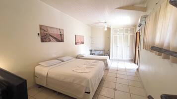 Habitación de hotel con cama, escritorio y silla. Se observa un armario y una ventana con cortinas.