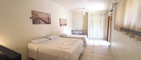 Ein Hotelzimmer mit Bett, Schreibtisch und Stuhl. Es gibt einen Kleiderschrank und ein Fenster mit Vorhängen.