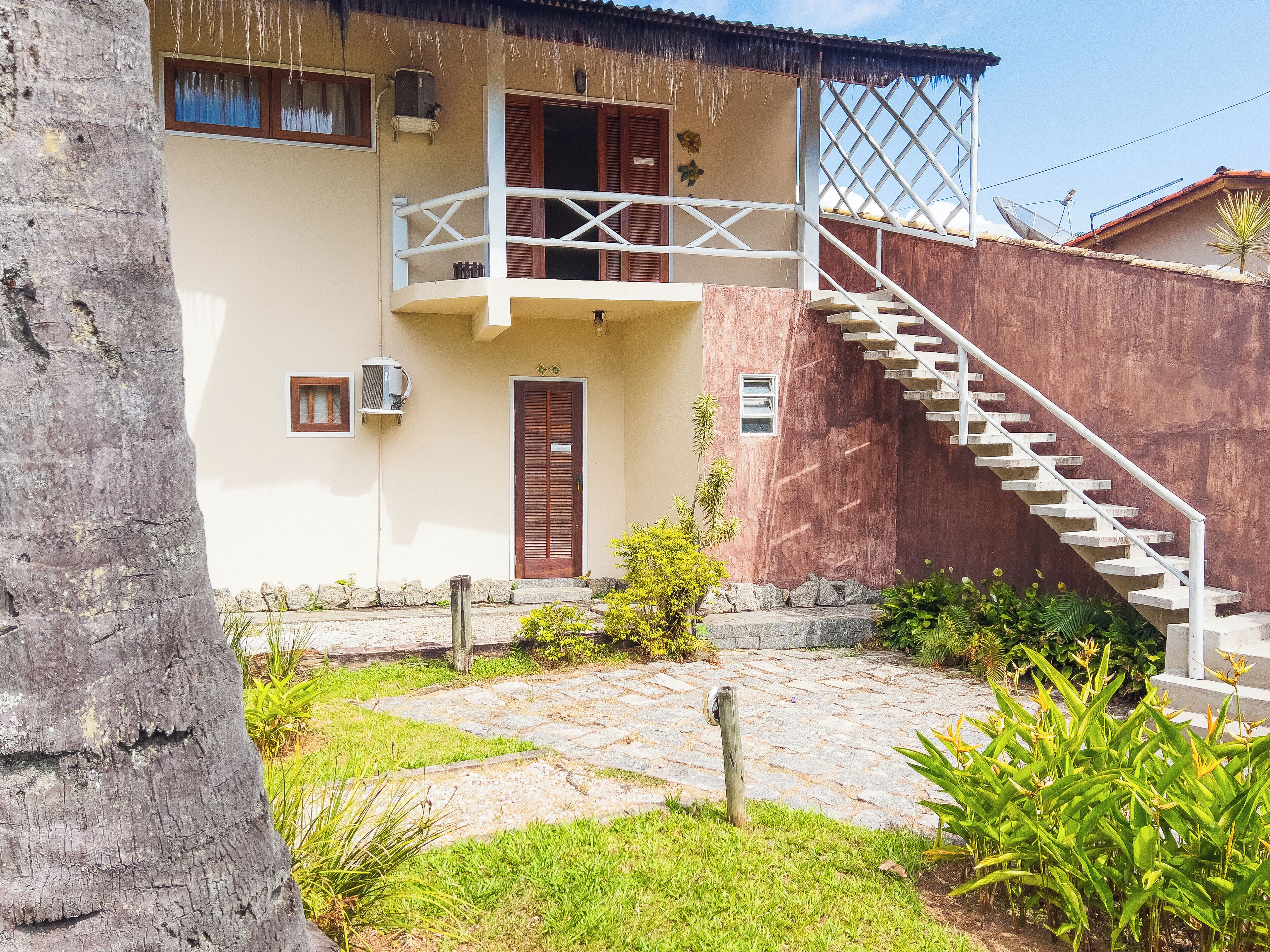 A two-story house with a balcony, a wooden door, and a staircase leading to the upper floor.