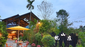 A garden area with a wooden fence, a table with chairs, and a yellow umbrella. - Zhen Shan Zhuang B&B (Yuanshan)