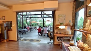 A restaurant with a wooden interior, a glass door leading outside, and a counter with food items. - Zhen Shan Zhuang B&B (Yuanshan)