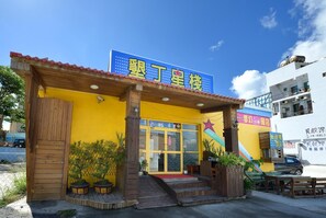 A building with a blue sign, wooden pillars, and a red awning. - Kstar 888 Bed and Breakfast (Hengchun)