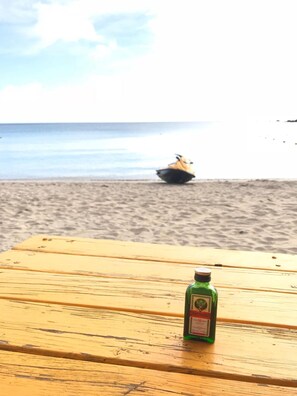 A wooden table with a green bottle on it, overlooking a beach with a yellow boat in the distance. - Kstar 888 Bed and Breakfast (Hengchun)