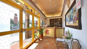 A hotel lobby with a large glass door, potted plants, a reception desk, and a wall with framed pictures. - Kstar 888 Bed and Breakfast (Hengchun)