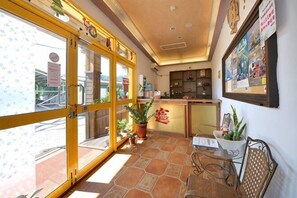 A hotel lobby with a large glass door, potted plants, a reception desk, and a wall with framed pictures. - Kstar 888 Bed and Breakfast (Hengchun)