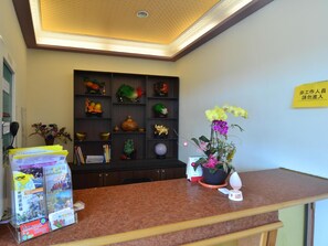 A reception desk with a bulletin board, a potted plant, and a sign on the wall. - Kstar 888 Bed and Breakfast (Hengchun)