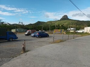 A parking lot with a blue car and a truck, surrounded by greenery and a mountain in the background. - Kstar 888 Bed and Breakfast (Hengchun)