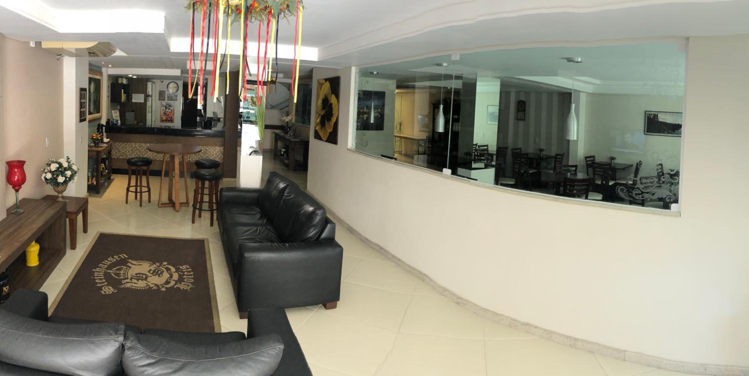 A modern living room with a black leather sofa, a coffee table, and a dining area with bar stools.