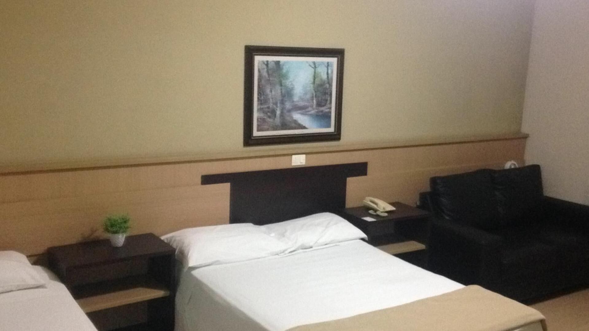 Una habitación de hotel con una cama, una mesita de noche, un escritorio, una silla y un cuadro en la pared.