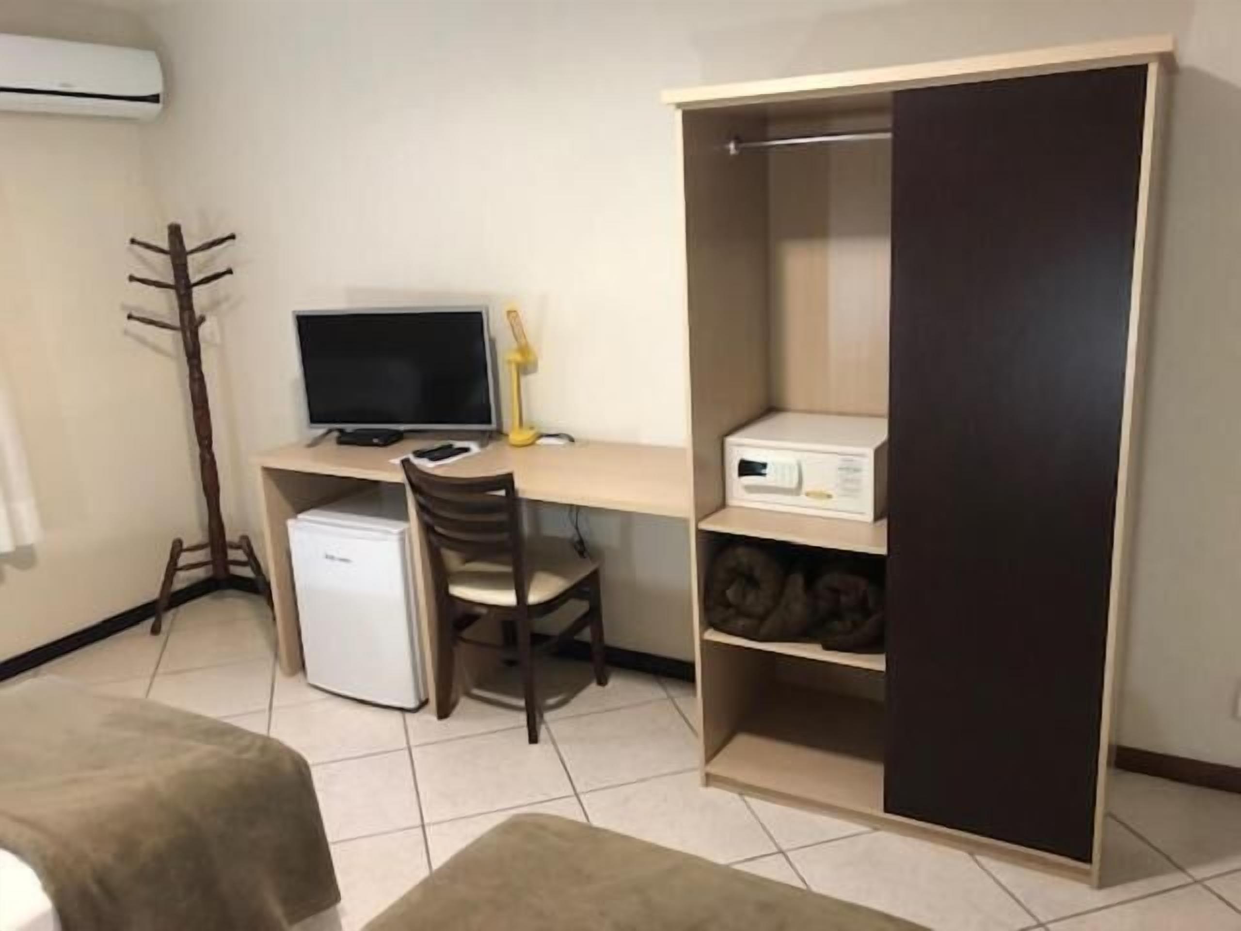 A compact room with a desk, chair, and a wardrobe.
